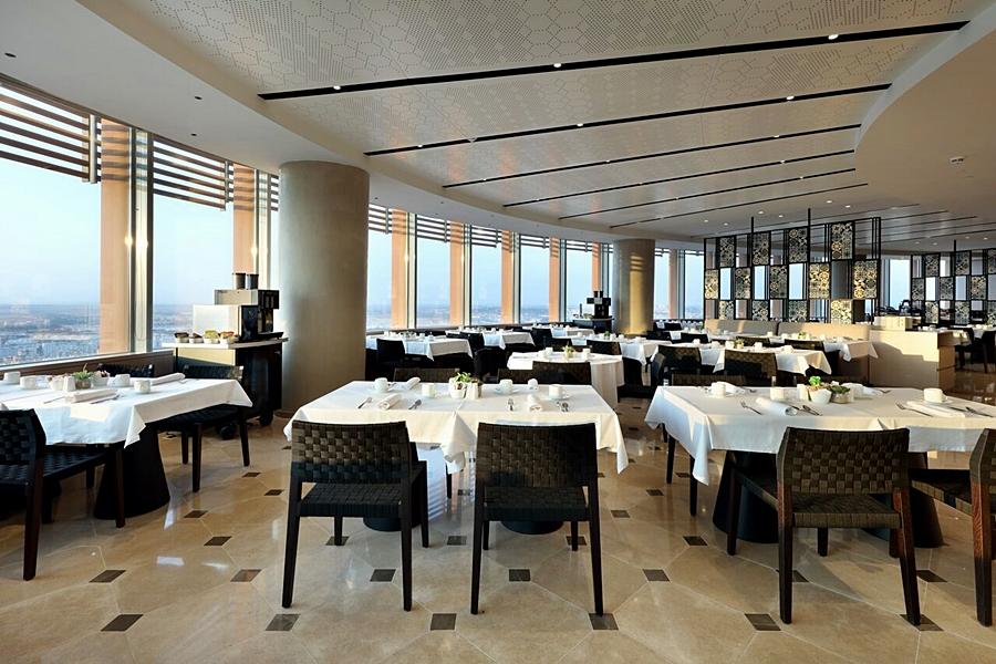 Eurostars Torre Sevilla Exterior foto The photo depicts the interior of a modern restaurant featuring a spacious dining area with multiple tables set elegantly with white tablecloths. The design includes large windows that allow natural light to flood the space and offer views of the out