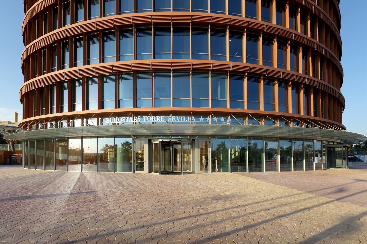 Eurostars Torre Sevilla Exterior foto The photo shows a modern building known as the "Cajasol Torre" located in Seville, Spain. It features a curved facade made of glass and metal, with multiple levels visible through large windows. The entrance is covered by a glass canopy, providing an