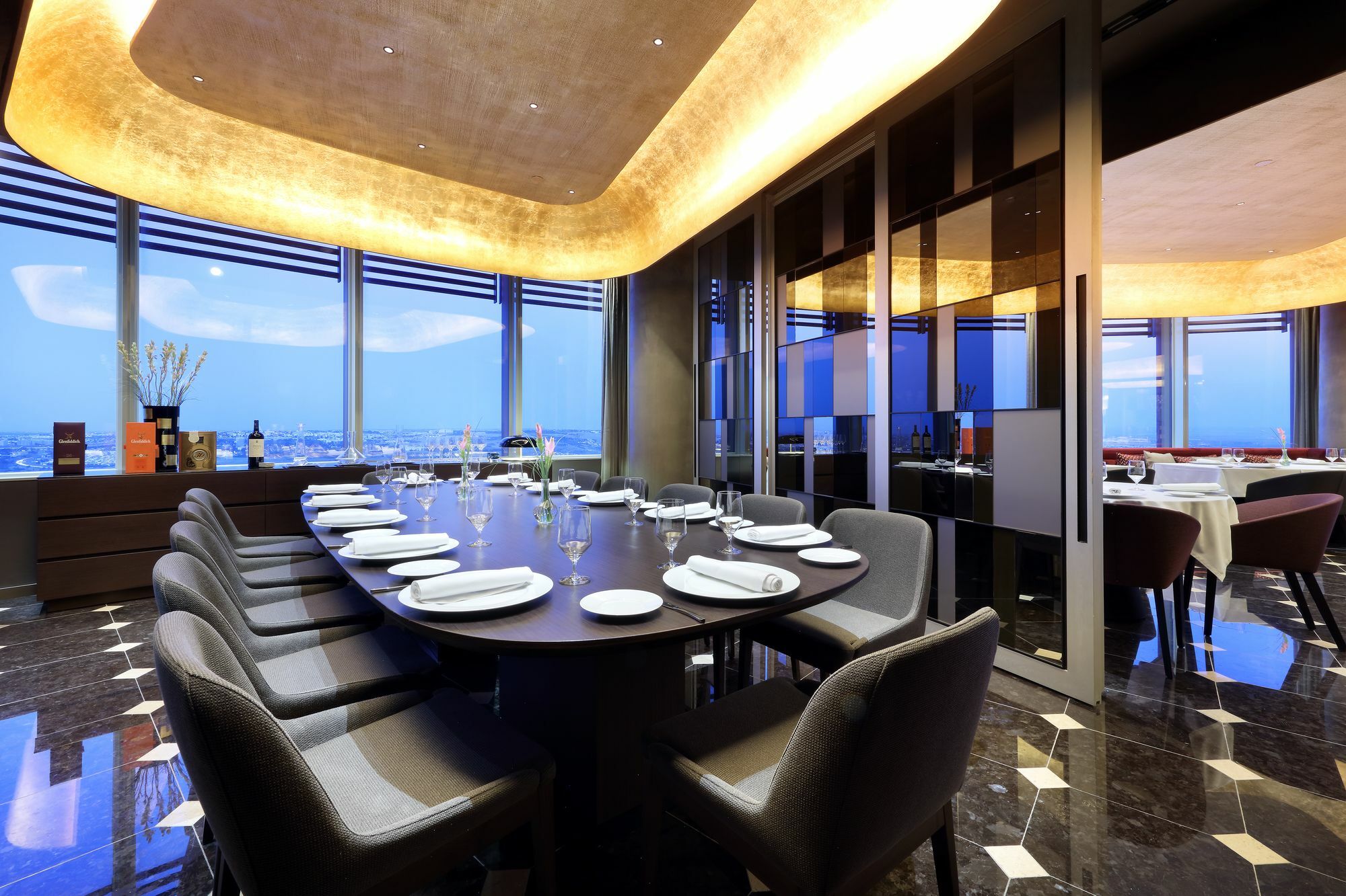 Eurostars Torre Sevilla Exterior foto The photo shows an elegant dining room with a long, dark wood table surrounded by plush chairs. The table is set with white plates and silverware, indicating it is ready for a meal. The room features large windows that offer a view of the outside, al